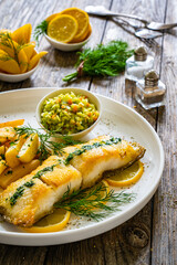 Fish dish - fried cod with French fries and cabbage salad on wooden table
