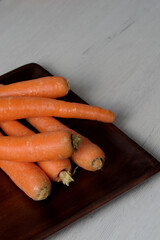 Raw carrots on a wooden tray