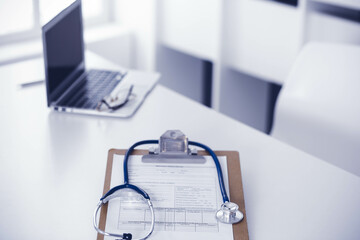 Stethoscope and clipboard with medication history records are on the table at the doctor's working place. Medicine and health care concept