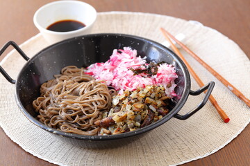 Shiitake mushrooms roasted with onion, soba noodles, radish topped with nori in a wok dish served with soy sauce