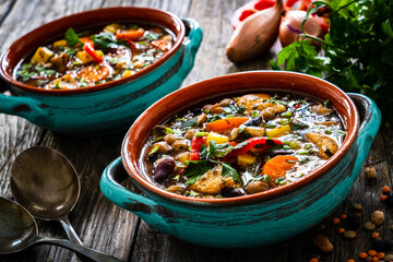 Delicious soup - cooked chicken breast boiled fresh vegetables, lentils, peas and chickpeas on wooden table
