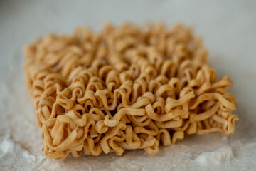 dried Instant noodles on white mulberry paper background. Instant noodles and pasta are wheat flour products call junk convenience food. Chinese and Japanese oriental noodle.
