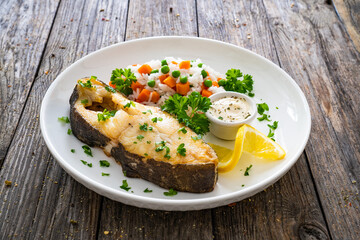 Fish dish - fried halibut with white rice, peas and carrots on wooden table
 - obrazy, fototapety, plakaty