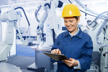 Woman engineer uses a digital tablet to control robots in a smart factory. Smart industry 4.0...