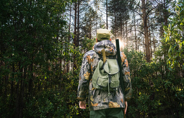 Fototapeta na wymiar Back view of hunter with a backpack and a gun 