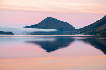 mountains reflected in the sea in pink light
