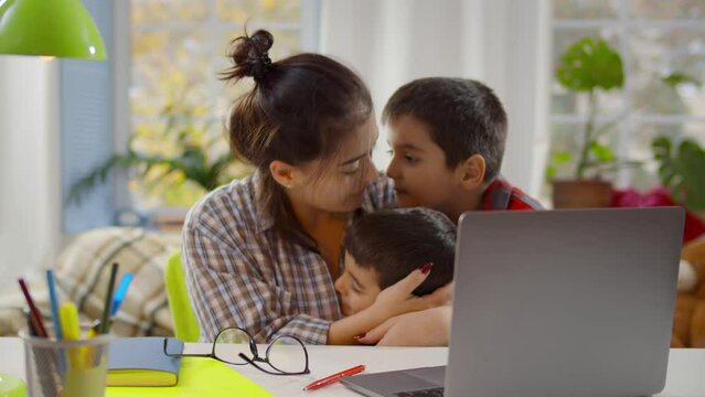Multitasking mother work on laptop and play with children at home. Realtime