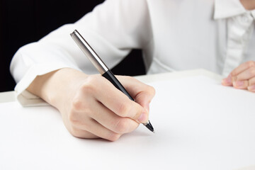 Young female hand will write something on a blank sheet of paper