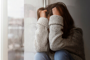 Unhappy Stressed Teen suffering Alone by Window. Depressed Teenage need Help and Support. Difficult...