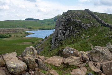 A stretch of Hadrian's Wall at milecastle 39 Roman military base, against backdrop of Whin Sill and Crag Lough lake in the distance. Northumberland National Park, UK