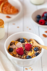 Breakfast bowl of oat flakes with berries, yoghurt and croissant