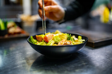 Chef cooking Caesar salad on restaurant kitchen