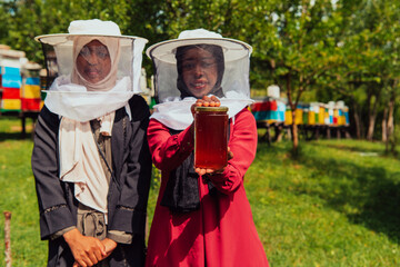 Portrait of a Arab investitors in the beekeeping department of a honey farm holding a jar of honey in her hand