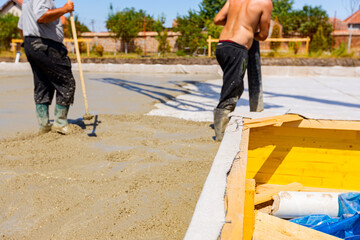 Verge of foundation mold made with wood boards on construction site. Worker holds pump hose to pour...