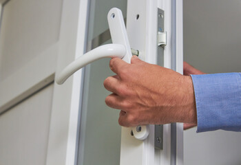 repair of plastic doors,installing a handle on a PVC door, a locksmith repairs a door lock - obrazy, fototapety, plakaty
