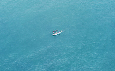 Naklejka na ściany i meble Aerial view of a fishing boat with fishermen in the blue ocean. Beautiful sea wallpaper for tourism and advertising. Asian landscape, drone photo