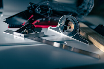 Carpenter’s protractor placed on the surface of table saw next to other measuring tools