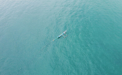 Aerial view of a fishing boat with fishermen in the blue ocean. Beautiful sea wallpaper for tourism and advertising. Asian landscape, drone photo