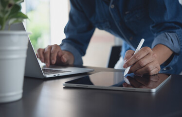 Close up of business man, freelancer working on laptop computer and digital tablet at office, online job, e-business concept
