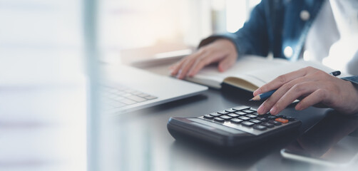 Business woman calculating monthly expenses, managing budget. Woman sitting at table using...