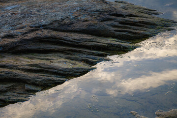 Detail of a immersed into sea water at sunset. Rock full of layers and cracks.