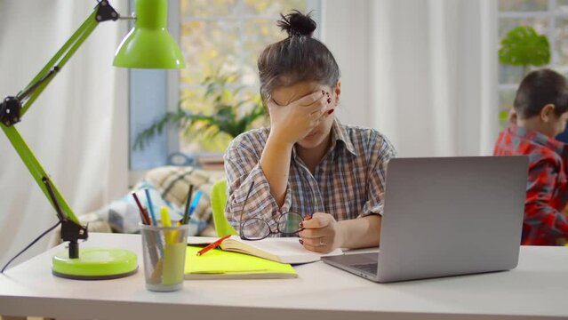 Beautiful stressed single mother struggling to work from home on laptop. Realtime