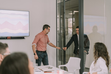 Middle-aged team leader welcoming his junior colleague