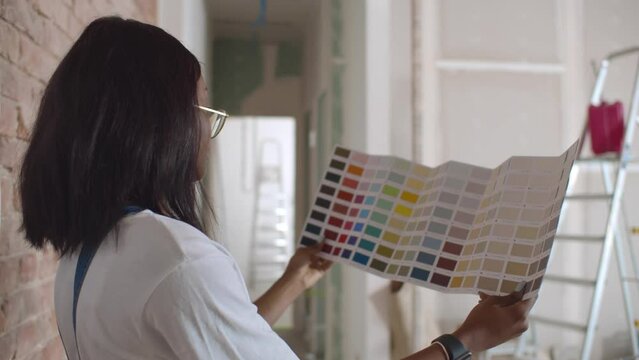 Close up woman homeowner choosing color from color sample swatch. Realtime
