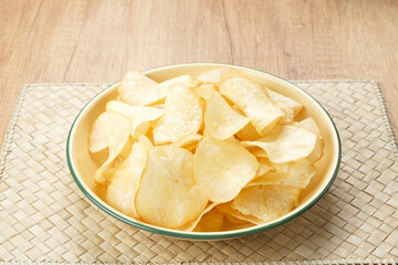 Keripik Singkong or Cassava Chips, Indonesian traditional snack. Served in bowl on wooden background.
