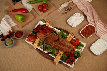 Video shooting of traditional Turkish kebab from top angle, bottom angle and side angle. There are oil pots, spices, yoghurt appetizers, spicy appetizers and  on the table. Horizontal videos.