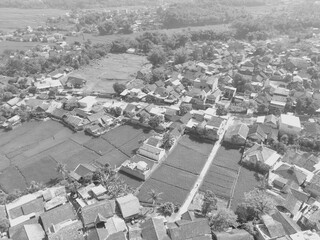 A black and white photo with a contrast between dense settlements and large rice fields in the Bandung area - Indonesia.