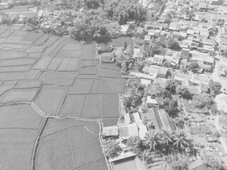 A black and white photo with a contrast between dense settlements and large rice fields in the Bandung area - Indonesia.
