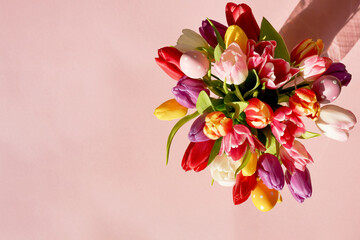 Colorful tulips bouquet with easter eggs on a pink background. Greeting easter card. Top view with copy space