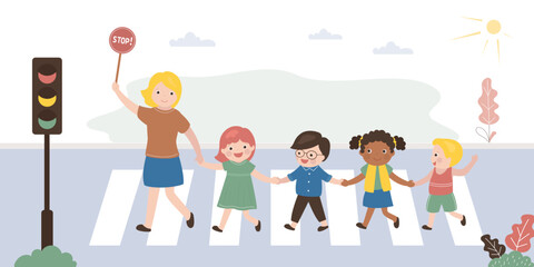 Fototapeta premium Caucasian educator or teacher with group of children cross road at crosswalk. Pedestrian safety, people follow rules of road. City view, urban road, traffic light. Multiethnic kids at street.