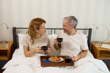 Mature couple enjoying coffee and breakfast in bed