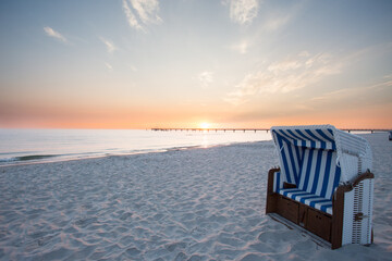 Fototapeta na wymiar Strandkorb weiß blau im Sonnenuntergang 