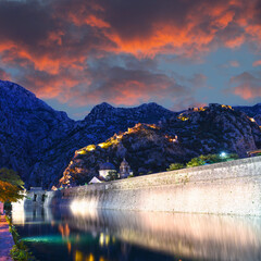Illuminated Old fortress of Kotor, Montenegro at night. Tower and wall, mountain at the background. Fortress wall at the background