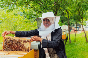 Hijab Arabian woman checking the quality of honey on the large bee farm in which she invested