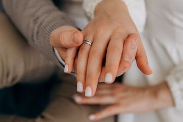 Obraz na płótnie Canvas Husband and wife holding hands with wedding rings close-up photo. Details of the wedding day. Gold wedding rings as a sign of strong love