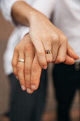 Husband and wife holding hands with wedding rings close-up photo. Details of the wedding day. Gold wedding rings as a sign of strong love