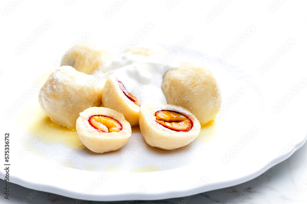 Poster plum dumplings with sour cream, powder sugar and melted butter