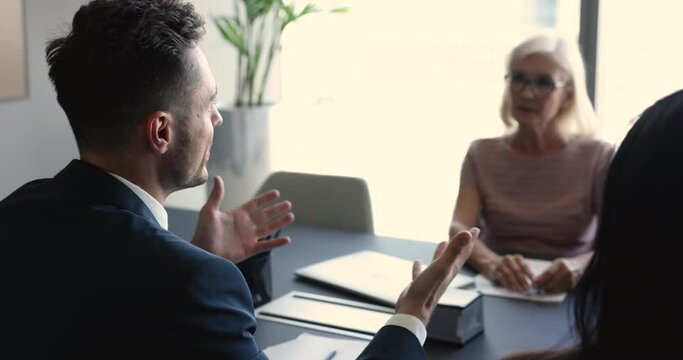 Businesspeople take part in negotiations in boardroom focus on young team leader, company executive manager, CEO makes speech, offer solution, express opinion, share experience at meeting with clients