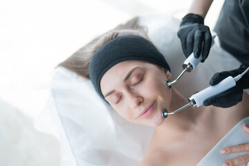 Young caucasian woman on microcurrent therapy procedure. Beautician's office.