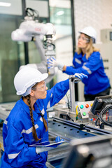 Two professional engineers or technician worker women help to check and maintenance robotic arm...