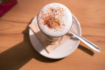 Coffee decorated with cinnamon on a wooden table in a plate and spoon.