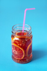 Fototapeta na wymiar red orange lemonade in glass jar with shadow on blue background