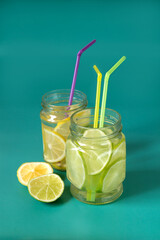 Lime and lemon lemonade in glass jars on a green background