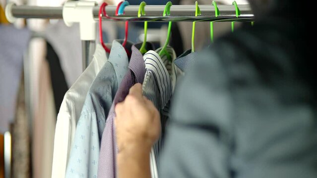 man choosing shirt on wardrobe hanger
