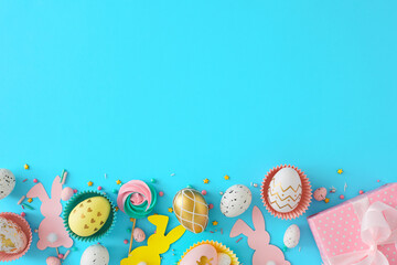 Easter decoration concept. Top view photo of color eggs and easter candy with chocolate sprinkles paper rabbits with gift box on pastel blue background with blank space.