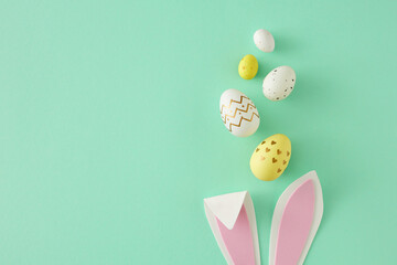 Easter concept. Top view photo of easter bunny ears yellow white eggs on isolated teal background with copy space. Holiday card idea - obrazy, fototapety, plakaty